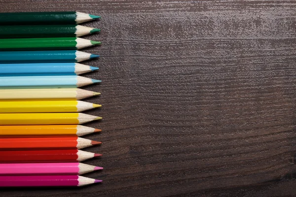 Lápices multicolores sobre el fondo de la mesa de madera marrón — Foto de Stock