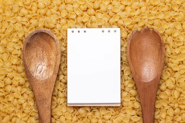 Houten lepels op droge ongekookt macaroni achtergrond — Stockfoto