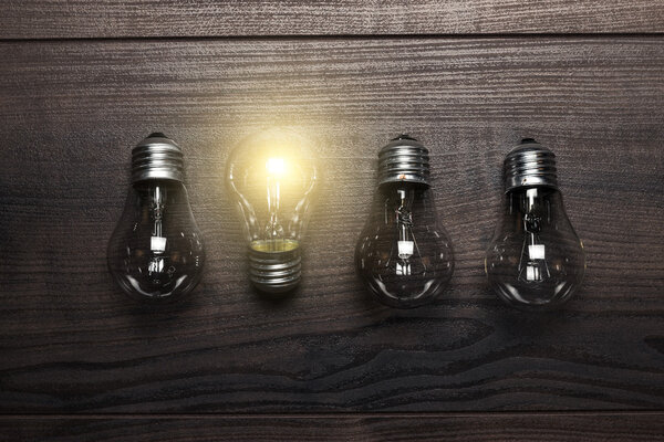 Glowing bulb uniqueness concept on wooden background