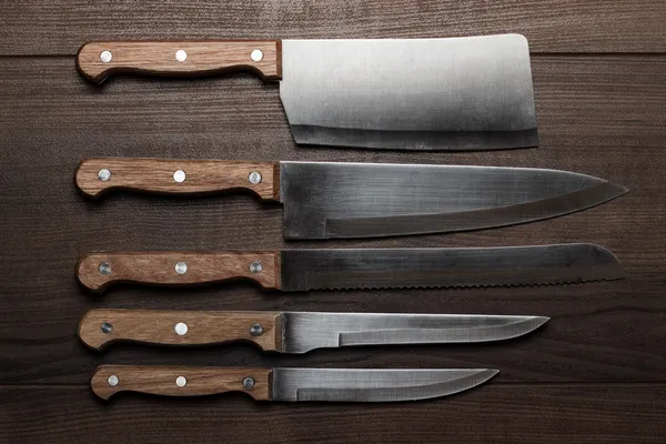 Kitchen knifes over brown wooden table — Stock Photo, Image