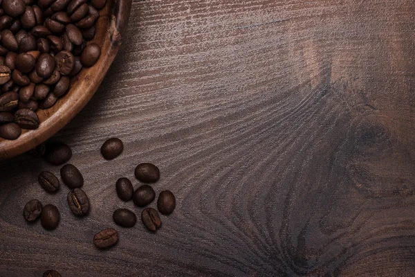 Grãos de café e tigela de madeira na mesa marrom — Fotografia de Stock