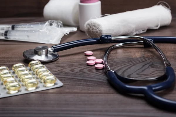 Statoscope and pills over brown wooden table — Stock Photo, Image