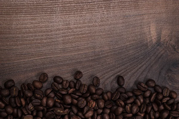 Chicchi di caffè sullo sfondo di legno marrone — Foto Stock