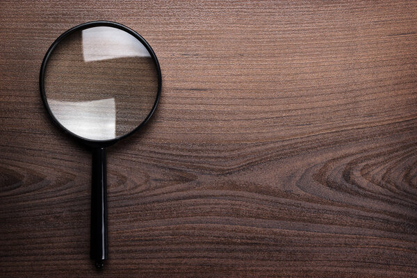 Magnifying glass on wooden background
