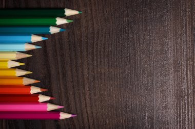 koyu kahverengi masa üzerinde renkli kalemler