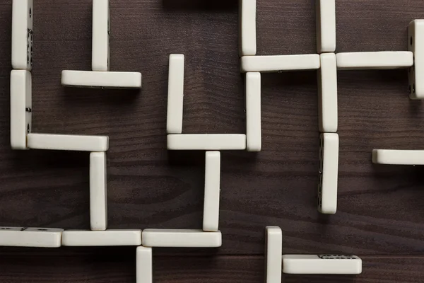 Domino pieces maze on wooden table background — Stock Photo, Image