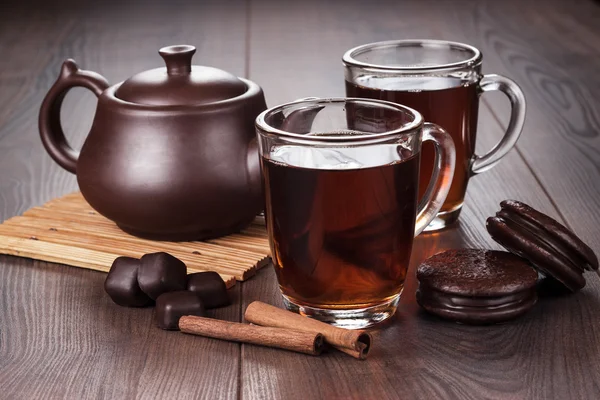 Xícara de chá com paus de canela e bule na mesa — Fotografia de Stock