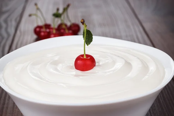 Cuenco blanco lleno de crema agria con cereza — Foto de Stock