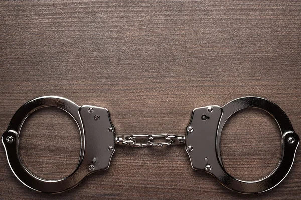 Steel handcuffs on the wooden background — Stock Photo, Image