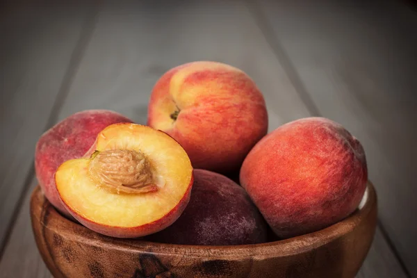 Träskål några färska persikor på bordet — Stockfoto