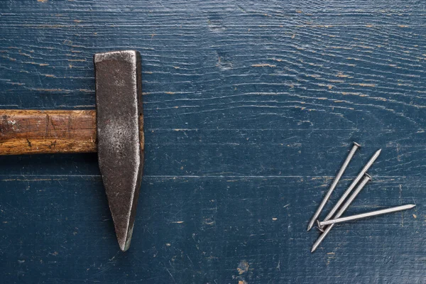 Oude hamer en nagels op blauwe tabel — Stockfoto