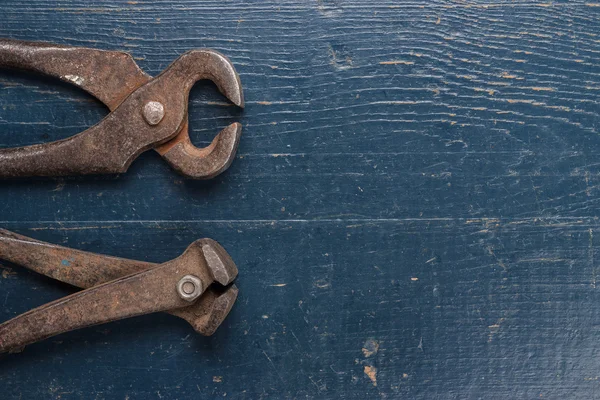 Old rusty tongs on blue table — Stock Photo, Image