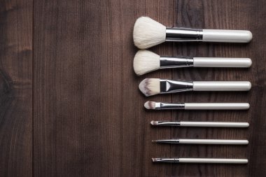 ahşap masa üzerinde beyaz makyaj fırçaları