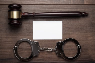 Handcuffs and judge gavel on wooden background clipart