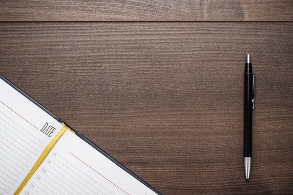 Cuaderno abierto y bolígrafo sobre mesa de madera — Foto de Stock