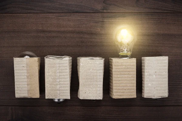 Glühende Glühbirne Einzigartigkeit Konzept auf Holz Hintergrund — Stockfoto