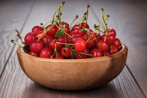 Houten kom kersen op tafel vol — Stockfoto