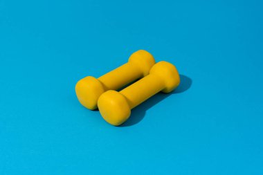 Mavi arka planda sarı halterlerin fotoğrafı.