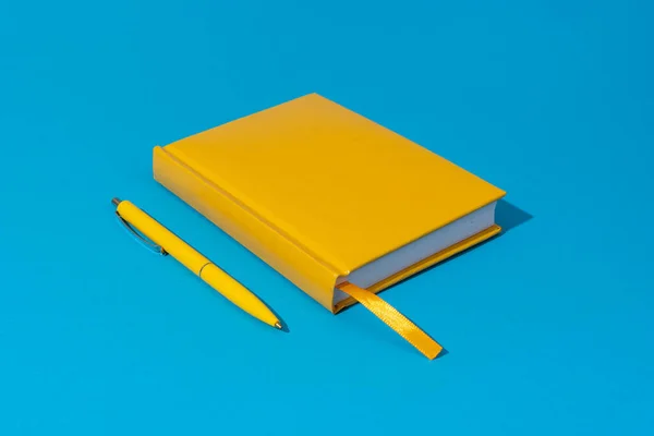 Вид зверху на ручку і блокнот на синьому фоні — стокове фото