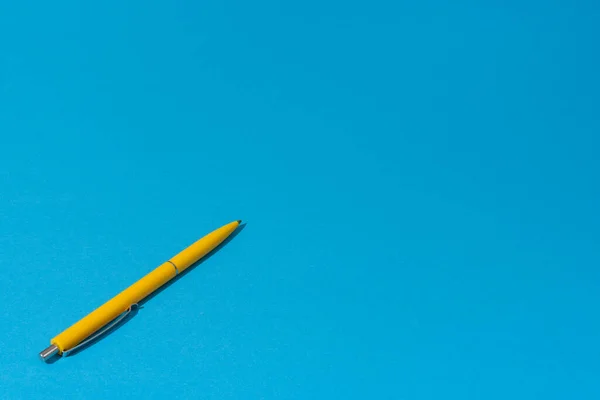 Photo of yellow ballpoint pen over blue background with copy space — Stock Photo, Image