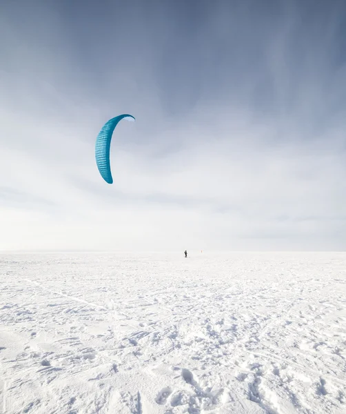 Kiteboarder with blue kite on the snow — Stock Photo, Image