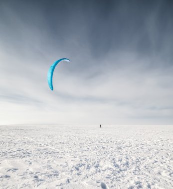 kiteboarder ile kar üzerinde mavi uçurtma