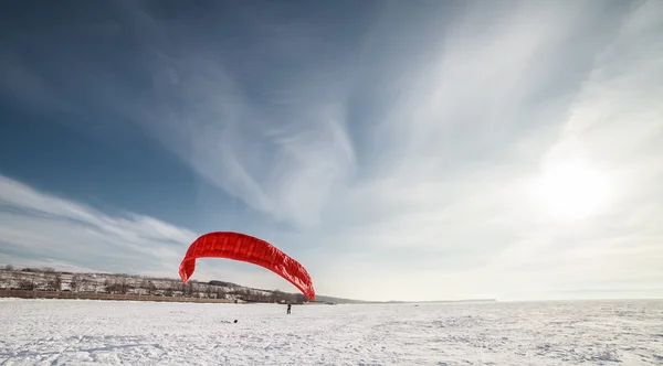 Kiteboarder con aquilone blu sulla neve — Foto Stock