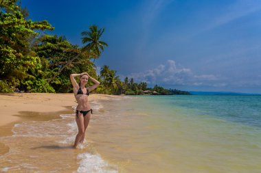 Genç bir kadın tropikal sahilde.