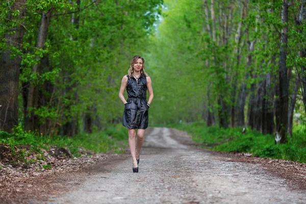 Элегантная женщина, идущая по проселочной дороге — стоковое фото