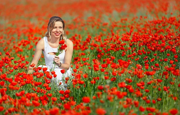 Beatiful woman in field of bright red poppy flowers in summer — Stock Photo, Image