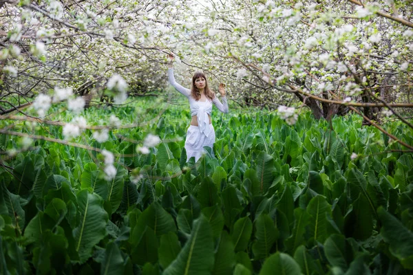 Chica en un jardín de primavera florecido — Foto de Stock