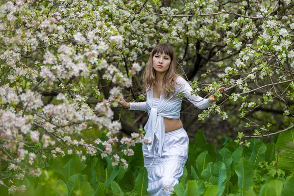 Chica en un jardín de primavera florecido — Foto de Stock