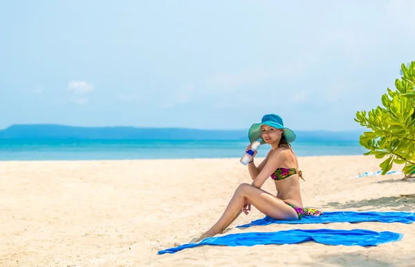 Meisje met een fles water op het strand — Stockfoto