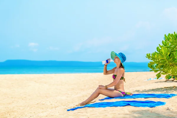 Meisje met een fles water op het strand — Stockfoto