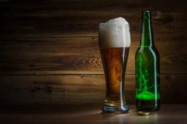 Beer glass and bottle on a wooden background — Stock Photo, Image