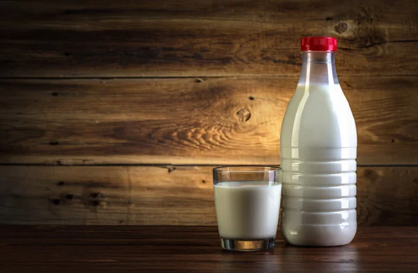 Vetro e bottiglia di latte su fondo di legno — Foto Stock