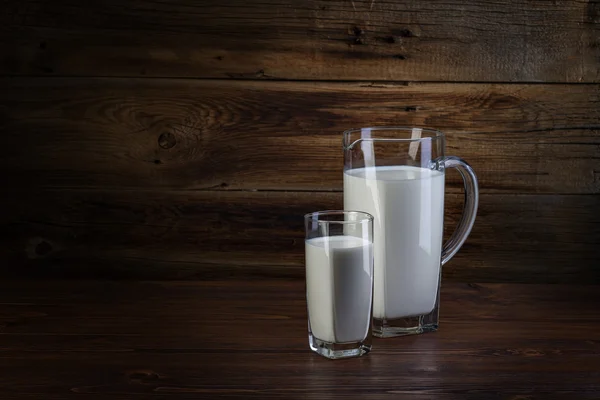 Vetro e caraffa di latte su fondo di legno — Foto Stock