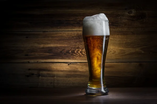 Glas Bier auf einem hölzernen Hintergrund — Stockfoto