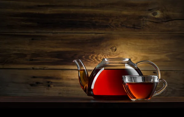 Glass teapot with black tea on wooden background — Stock Photo, Image