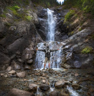 Şelalenin önünde sırt çantalı bir turist.