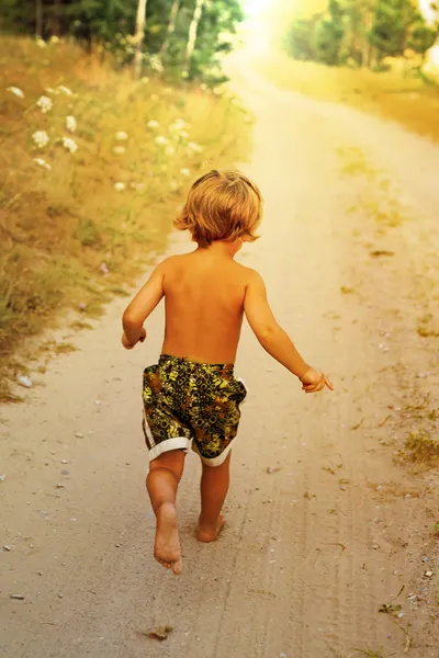 Chłopiec biegną wzdłuż drogi w parku, odkryty — Zdjęcie stockowe