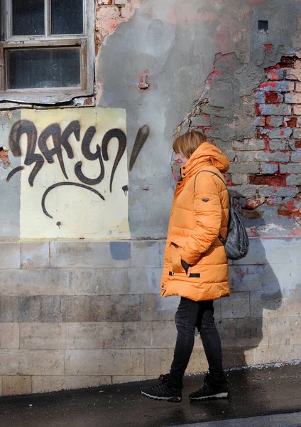 Mujer Con Abrigo Amarillo Camina Por Calle Contra Fondo Pared — Foto de Stock