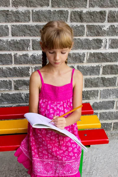 Girl draws on the album sitting bench — Stock Photo, Image