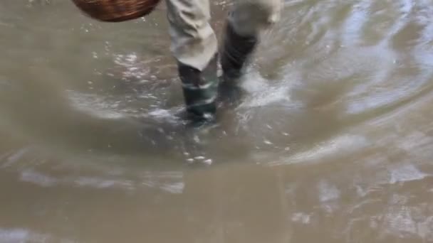 Hombre con botas de goma camina sobre el agua — Vídeo de stock