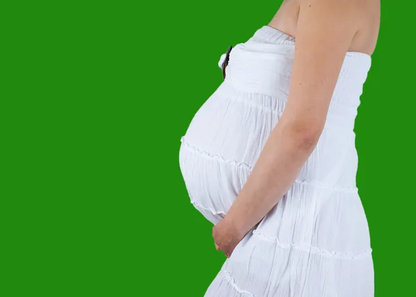 Беременный живот с руками на нем изолированы на зеленом фоне — стоковое фото
