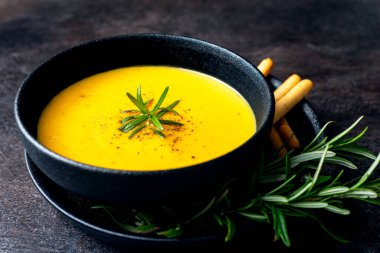 Koyu arkaplanda keten peçeteli balkabağı çorbası.