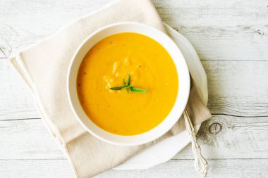 Arka planda keten peçeteli balkabağı çorbası.