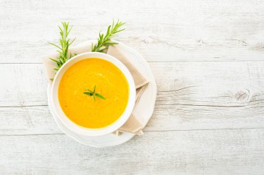 Arka planda keten peçeteli balkabağı çorbası.