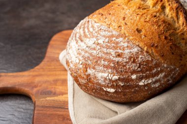 Kahverengi doğrama tahtasındaki keten kumaşa ekşi ekmek..