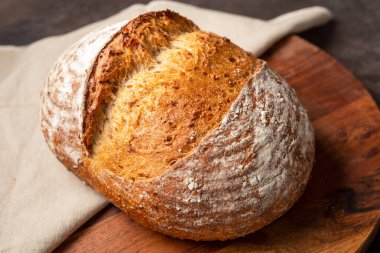 Kahverengi doğrama tahtasındaki keten kumaşa ekşi ekmek..